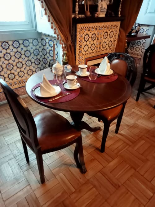 Elegant dining room at Patio Da Villa guesthouse in Coruche with round wooden table, formal place settings, and traditional