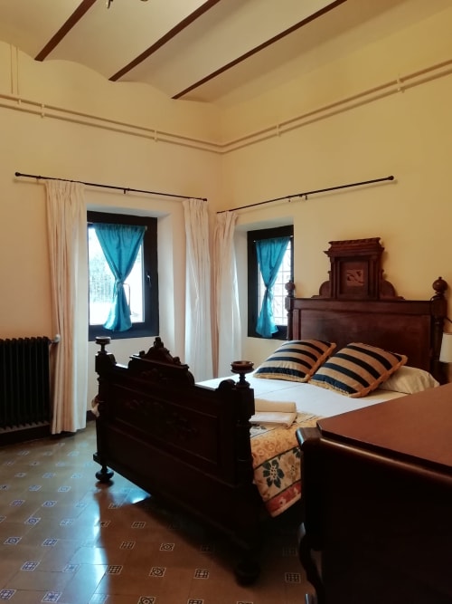 Habitación Ou de Reig|Sant Martí de Centelles -Aposento situado en la planta noble de la masía, con vistas al Turó de l’Antiga y a la antigua hacienda; a la que se accede por un amplio y elegante salón, núcleo de acceso en las grandes cámaras de la masía. Esta sala conserva gentiles mesas, sillas y butacas, para poder leer, estar en familia haciendo sobremesa o sencillamente descansar.
