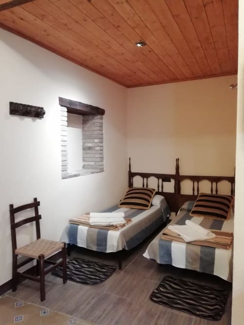 Habitación Ou de Reig|Sant Martí de Centelles -Aposento situado en la planta noble de la masía, con vistas al Turó de l’Antiga y a la antigua hacienda; a la que se accede por un amplio y elegante salón, núcleo de acceso en las grandes cámaras de la masía. Esta sala conserva gentiles mesas, sillas y butacas, para poder leer, estar en familia haciendo sobremesa o sencillamente descansar.