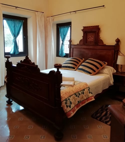 Habitación Ou de Reig|Sant Martí de Centelles -Aposento situado en la planta noble de la masía, con vistas al Turó de l’Antiga y a la antigua hacienda; a la que se accede por un amplio y elegante salón, núcleo de acceso en las grandes cámaras de la masía. Esta sala conserva gentiles mesas, sillas y butacas, para poder leer, estar en familia haciendo sobremesa o sencillamente descansar.
