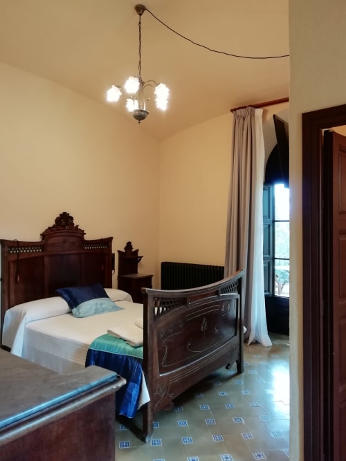 Habitación Fredolic|Sant Martí de Centelles-Aposento particularmente espacioso, cubierto con vuelta de arco redondo, cálido y con mucha luz natural, situado en planta noble de la masía; con vistas a la antigua era, a los jardines de a mediodía y a la piscina de agua salada, dispuesta para los huéspedes en estaciones templadas.