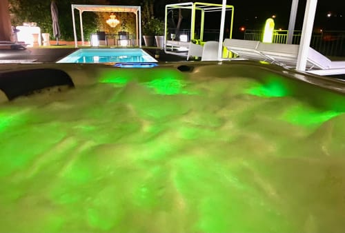Piscine à débordement illuminée aux éclairages ambiants verts de la Villa Colina, vue nocturne à Mandelieu-la-Napoule
