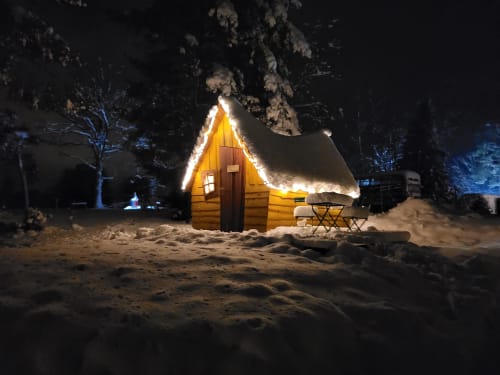 Gemütliches beleuchtetes Holzchalet in Les Refuges Du Chalet in Jalhay, Belgien, eingebettet in verschneitem Garten bei Nacht