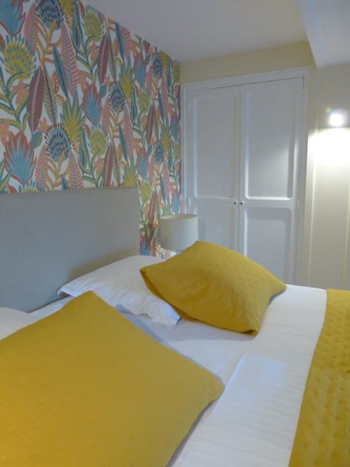 Bedroom with yellow bedding and colorful floral wallpaper at Villa Thébaïde, Laudun L'Ardoise