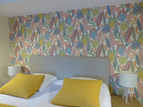 Modern bedroom with colorful floral wallpaper, gray headboard, yellow pillows at Villa Thébaïde B&B in Laudun, France