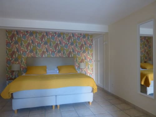 Lavande room at Villa Thébaïde with yellow bedding, floral headboard, and garden views in Laudun L'Ardoise