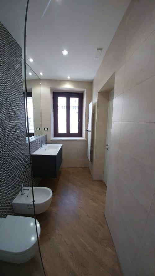 Modern bathroom in Stella CasaBono hotel suite, Sulmona featuring glass shower, black vanity, and wood flooring