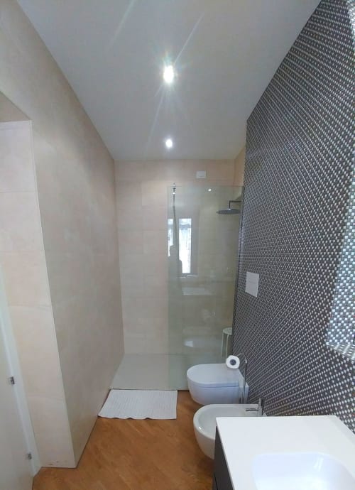 Modern bathroom at Stella CasaBono hotel in Sulmona with shower, toilet, bidet, mosaic tiles, and wooden flooring