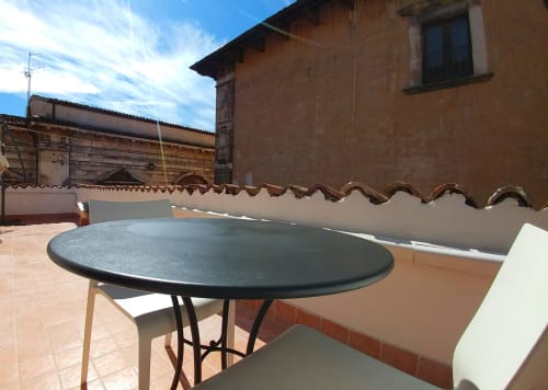 Terrace at Stella CasaBono hotel in Sulmona with round table, blue umbrella, and historic Italian architecture views
