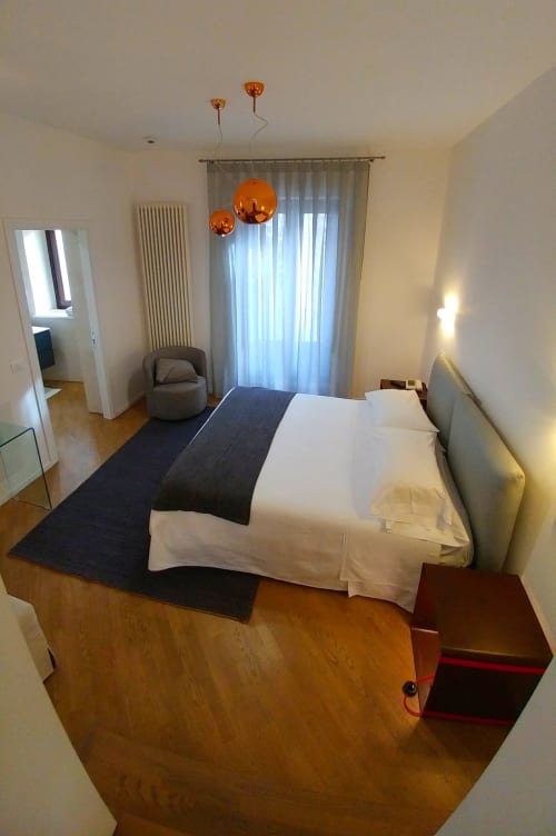Modern hotel suite bedroom at Stella CasaBono in Sulmona with white bedding, copper pendant lights, and balcony doors with