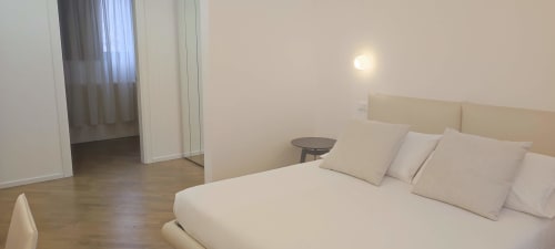 Bright junior suite bedroom at Stella CasaBono hotel in Sulmona with cream bedding, beige headboard, and wooden floors