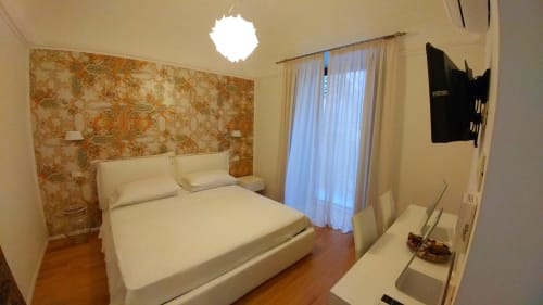 Suite De Luxe bedroom at Stella CasaBono hotel in Sulmona with queen bed, floral accent wall, flat-screen TV, and balcony