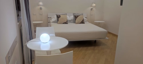 Stella CasaBono Junior Suite with queen bed, decorative pillows, modern round table with lamp, and wooden flooring in Sulmona
