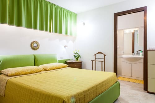 Camera luminosa con testata verde, biancheria gialla e bagno ensuite presso Affittacamere Al Mare a Torre Grande, Oristano