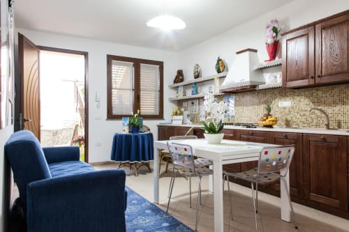 Moderna zona cucina-soggiorno presso Al Mare & Acquamarina a Torre Grande Oristano con mobili in legno, tavolo bianco e blu