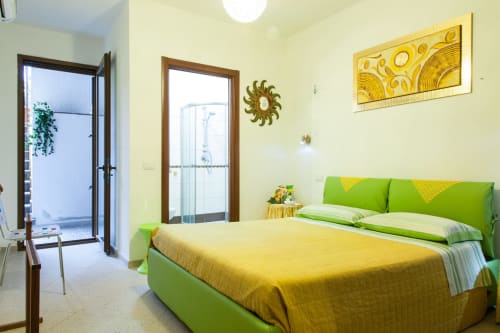 Bright bedroom with green bed, yellow bedding, and balcony access at Affittacamere Al Mare in Torre Grande, Oristano