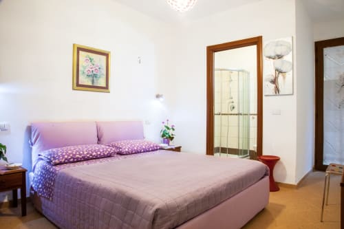 Spacious bedroom with pink bed, en-suite bathroom, and modern amenities at Affittacamere Al Mare, Torre Grande Oristano