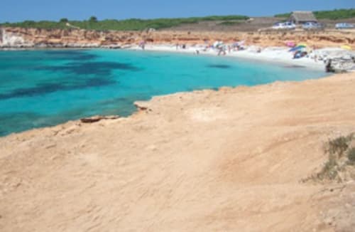 Acque turchesi e spiaggia sabbiosa a Torre Grande Oristano con bagnanti e ombrelloni colorati