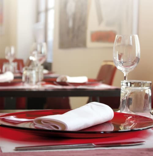 Elegant formal dining setup at Stella CasaBono with red plates, white napkin, wine glasses in Sulmona