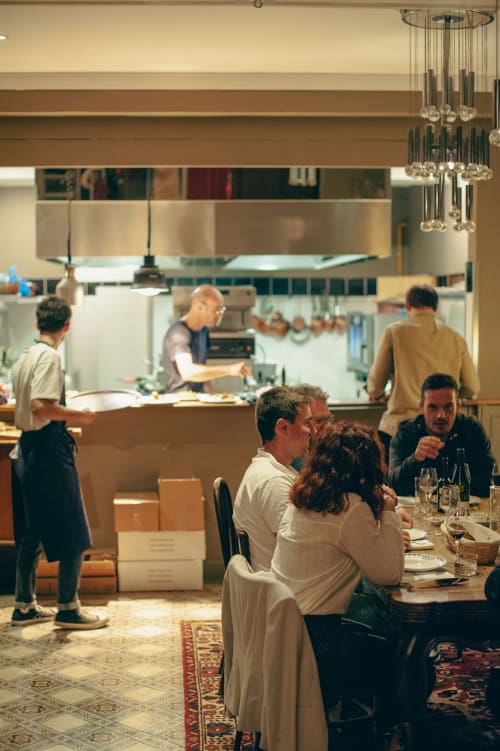 Clients dînant au restaurant Mas De Lafeuillade à Montpellier avec vue sur la cuisine ouverte et éclairage suspendu