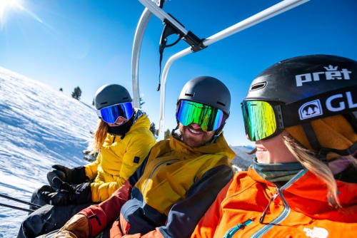 Gruppo di sciatori sulla seggiovia che godono di una splendida giornata di sole alla stazione sciistica di Aprica, Italia