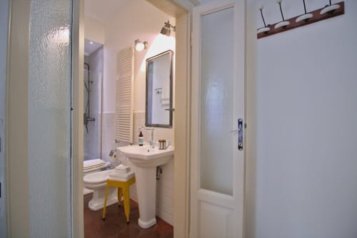 Moderno bagno a Porta Tosa Milano con lavabo su piedistallo, specchio, wc, doccia e scaldasalviette