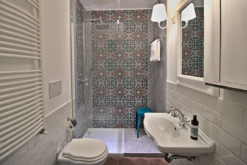 Bagno moderno a Porta Tosa Milano con doccia in piastrelle decorate, doppio lavabo e scaldasalviette