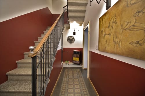 Elegante corridoio a Porta Tosa Milano con muri in terracotta, scala e opere d'arte ornamentale