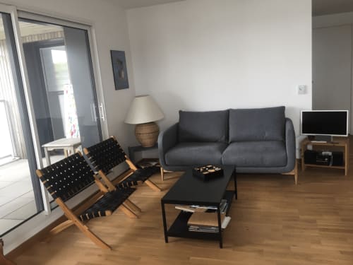 Salon moderne de l'hôtel Mer et Maisons à La Trinité sur Mer avec canapé gris, chaises noires et parquet