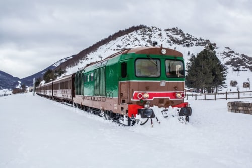 Vintage green and red train in snowy landscape near Stella CasaBono hotel in Sulmona