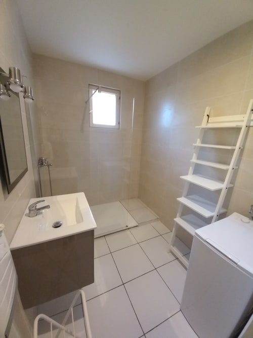 Salle de bain moderne et épurée au gîte Sylvie CAMBON à Montséret avec lavabo, toilettes, douche et rangements blancs