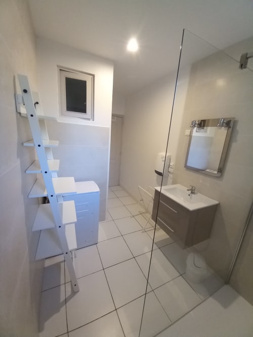 Salle de bains moderne au gîte Sylvie CAMBON à Montséret avec vasque blanche, miroir, porte-serviettes et douche vitrée