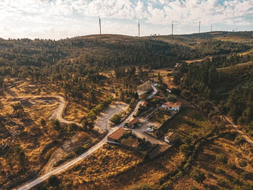 Paisagem serena dos Moinhos d’Antoninha: um equilíbrio perfeito entre a arquitetura tradicional, a vegetação natural e as torres eólicas que pontuam o horizonte da Serra de Leomil.