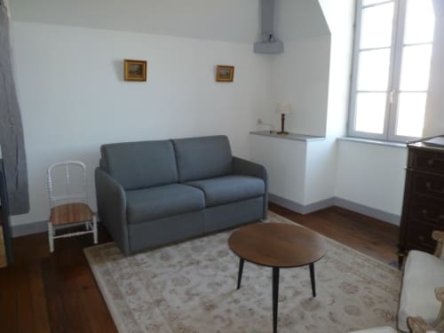 Salon de la chambre Lila au Château De Clusors avec canapé gris, table ronde en bois et mobilier d'époque à St Menoux