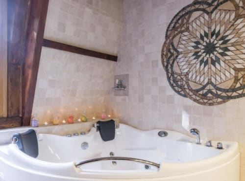 Baignoire balnéo luxueuse au Moulin d'Ajon avec art mural décoratif et bougies d'ambiance