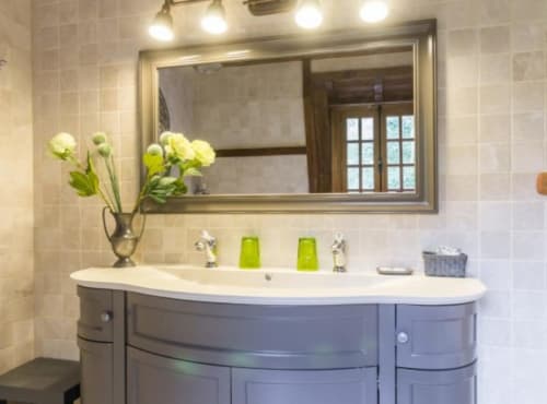 Salle de bains élégante avec vasques doubles, miroir et fleurs jaunes fraîches au Moulin d'Ajon