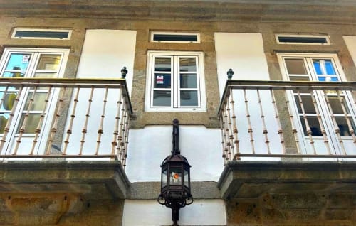 Fachada del apartamento Holibai en Baiona con balcones, contraventanas blancas y farola