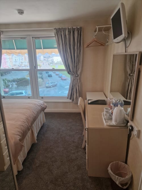 Double room with sea view at The Sands Hotel in Paignton, featuring bed, desk, TV, and coastal outlook