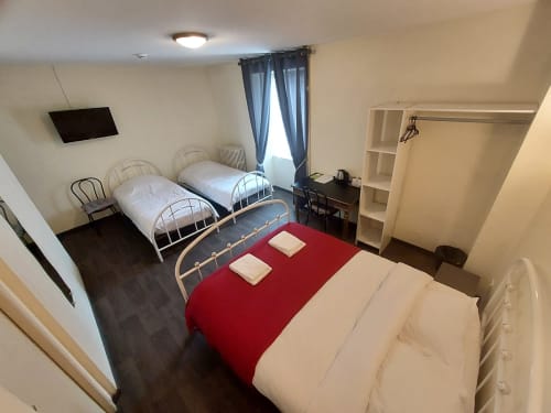 Chambre Le Comtois à Saône avec plusieurs lits, accents rouges et équipements modernes