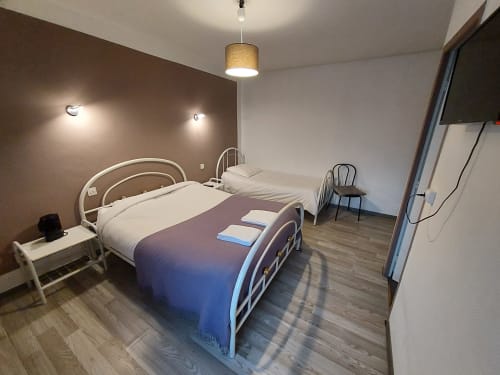 Chambre moderne de la maison d'hôtes Le Comtois en Saône avec deux lits, éclairage suspendu et parquet