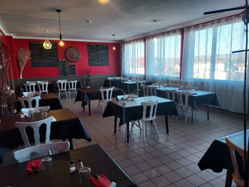Salle à manger Le Comtois à Saône avec murs rouges, chaises blanches modernes et vue sur la ville