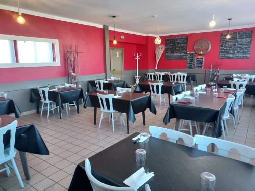 Salle à manger du restaurant Le Comtois aux murs roses, tables noires, chaises blanches et tableaux de menus à Saône, France
