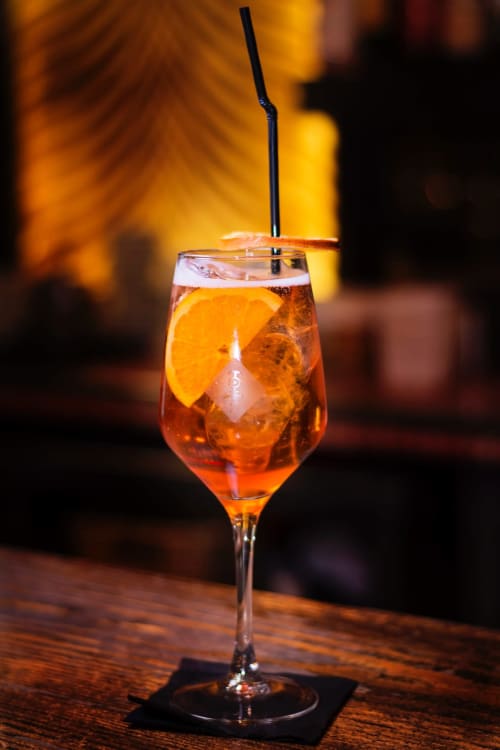 Cocktail vibrant avec tranche d'orange et glaçons au Gîte Le Comtois en Saône, France