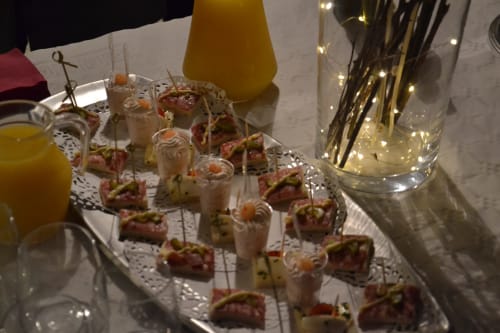 Élégant plateau de desserts du Comtois avec pâtisseries gourmandes et mousses, accompagnés de boissons jaunes et éclairage ambiant.