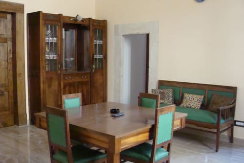 Loungebereich des Hotels Stella CasaBono in Sulmona mit Holzmöbeln, grünen gepolsterten Sitzmöbeln und Glasschiebetür-Vitrine