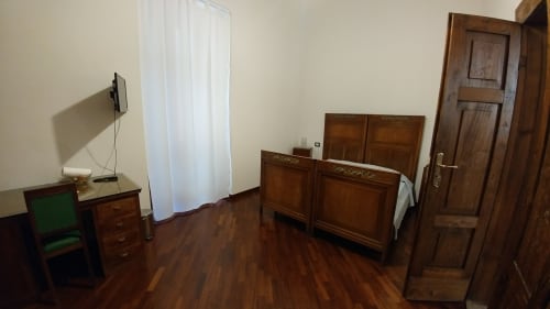 Zimmer des Hotels Stella CasaBono in Sulmona mit Holzmöbeln, Schreibtisch mit Monitor und Parkettboden