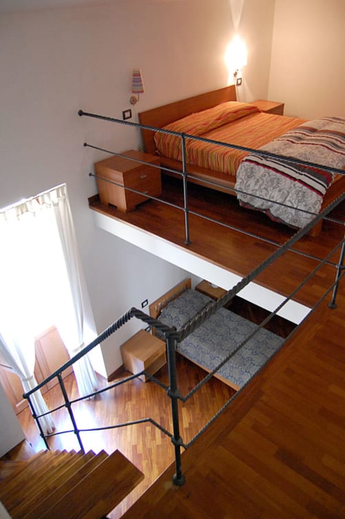 Etagenbetten mit gestreifter Bettwäsche im Hotel Stella CasaBono in Sulmona, mit Metallgeländern und Holzplattform.
