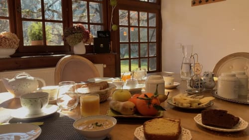 Table du petit-déjeuner à La Bageatière B&B à Lépin-le-Lac avec viennoiseries fraîches, fruits, jus et vue sur la campagne