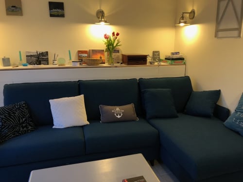 Salon moderne avec canapé sectionnel bleu foncé, table basse blanche et étagère avec objets de décoration à Belle Île en