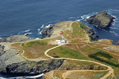 Phare blanc perché sur falaises herbeuses dominant la côte rocheuse de Belle-Île-en-Mer, vue aérienne